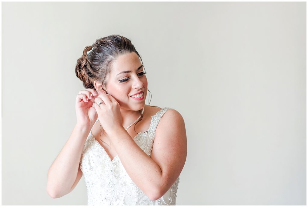 bride is putting her earrings in on her wedding day