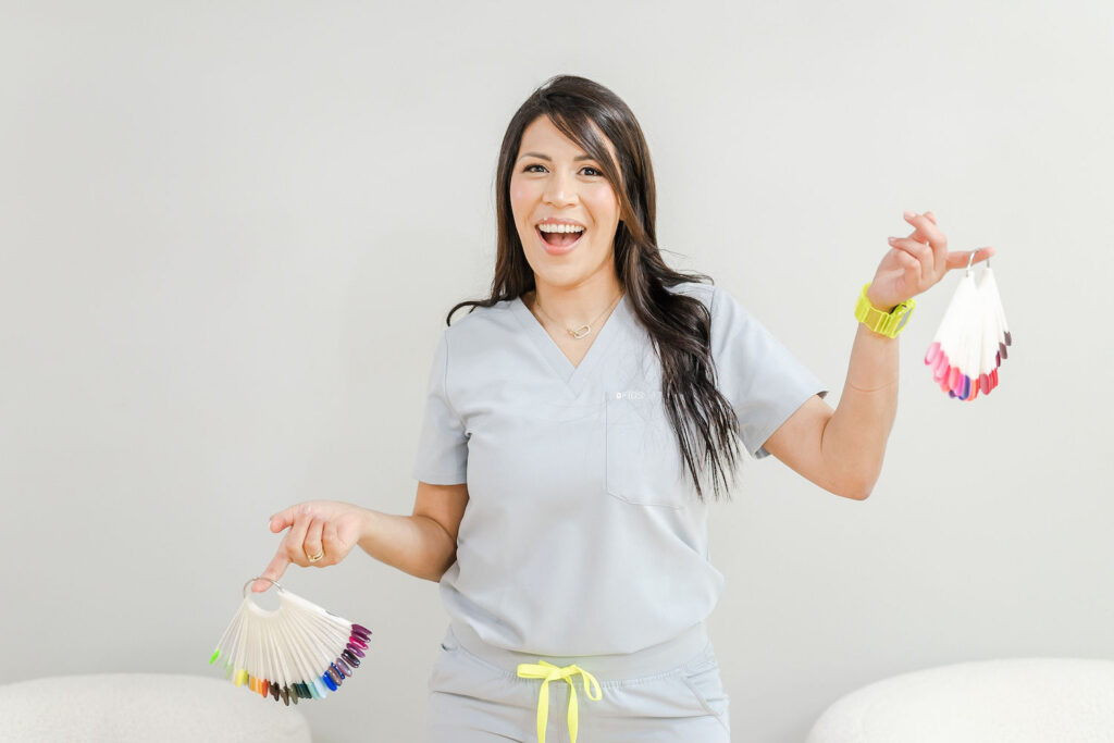 nail artist smiling while holding up nail colors