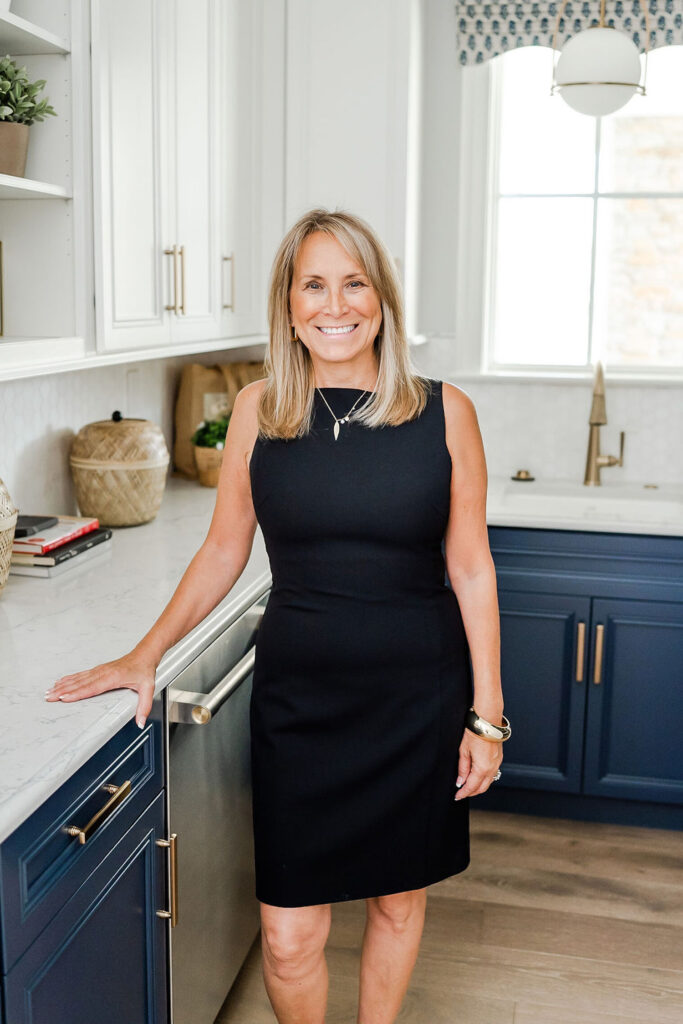 headshot of a realtor in a black dress while standing in a kitchen