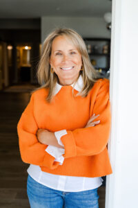 blonde woman in an orange sweater smiling during a branding session