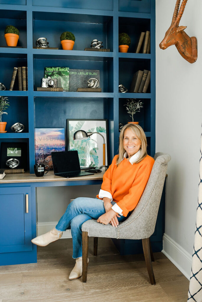woman in orange sitting in a chair at a blue desk during a branding session