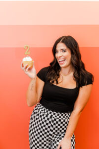 woman smiling while holding a cupcake