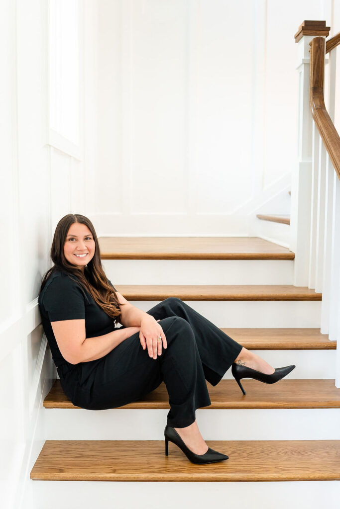 headshot of luxe local real estate agent in black outfit, sitting on the stairs