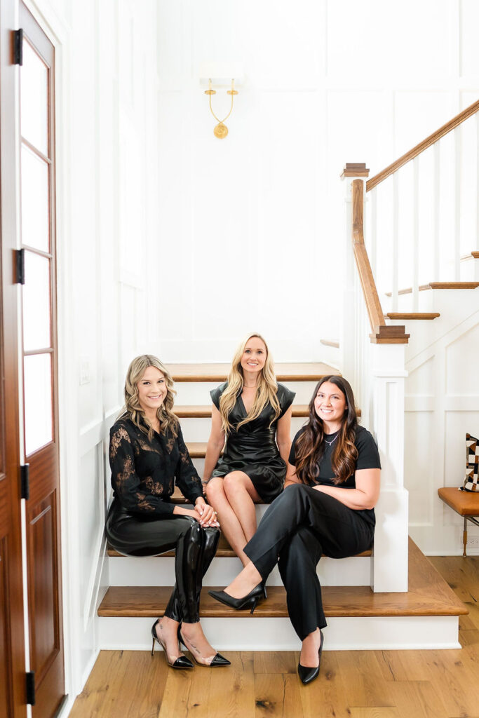 Team of real estate agents sitting together on the stairs, dressed in black outfits — showcasing a united team presence.