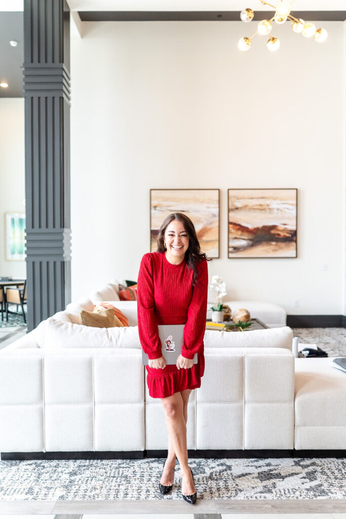 woman in red dress smiling and holding a laptop during a branding session for a realtor