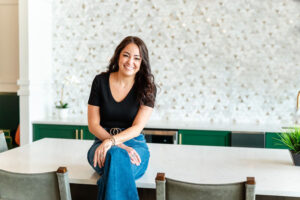 woman in black shirt smiling and sitting on a table during a branding session for a realtor