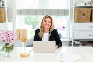 woman in black blazer smiling while sitting at a table with a laptop in front of her during a branding session