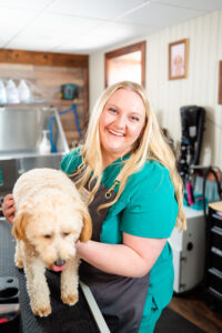 blonde pet groomer smiling while petting a little dog during a branding session