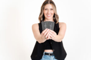 woman in black vest and jeans smiling during branding photos for a bridal beauty company