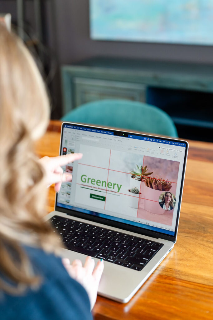 woman pointing to her laptop which shows visual designs she has created