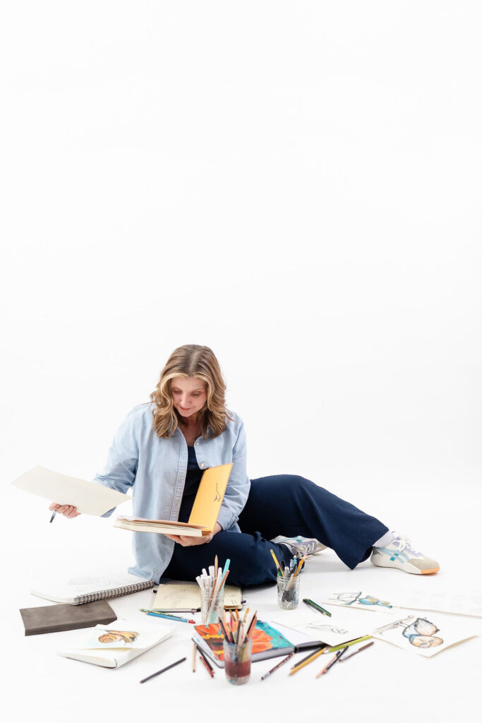 woman sitting on the ground with art supplies around her during an online coach branding session