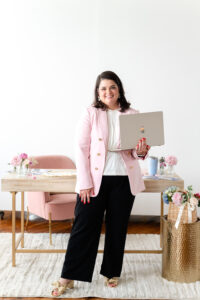 wedding planner holding a laptop while standing by a desk in a branding session