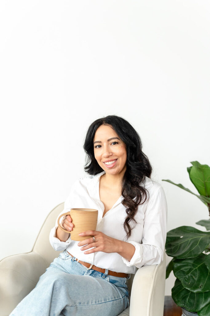 woman in white blouse smiling while holding a coffee during an art therapist branding session