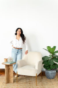 art therapist in jeans and a white blouse standing by a chair during a branding session