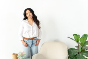 art therapist in jeans and a white blouse standing by a chair during a branding session