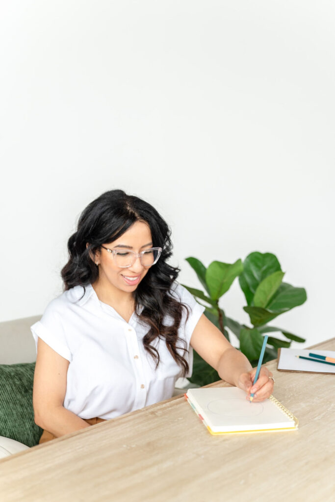 woman in white blouse smiling while writing on paper during a branding session