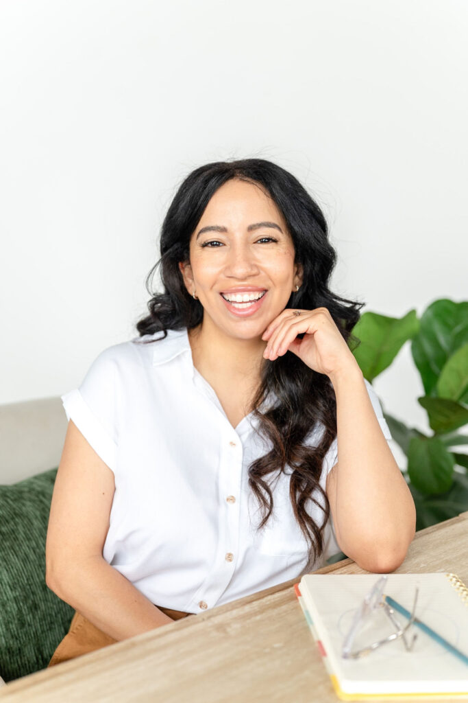 art therapist in a white blouse smiling while sitting at a table during a branding session