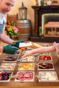 woman handing charcuterie plate to a customer during a charcuterie branding session